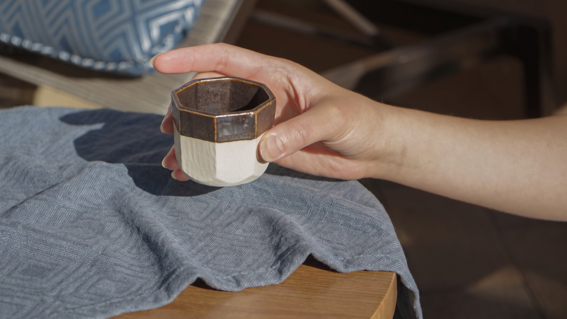 Hand holding a two-tone octagonal tea cup outdoors