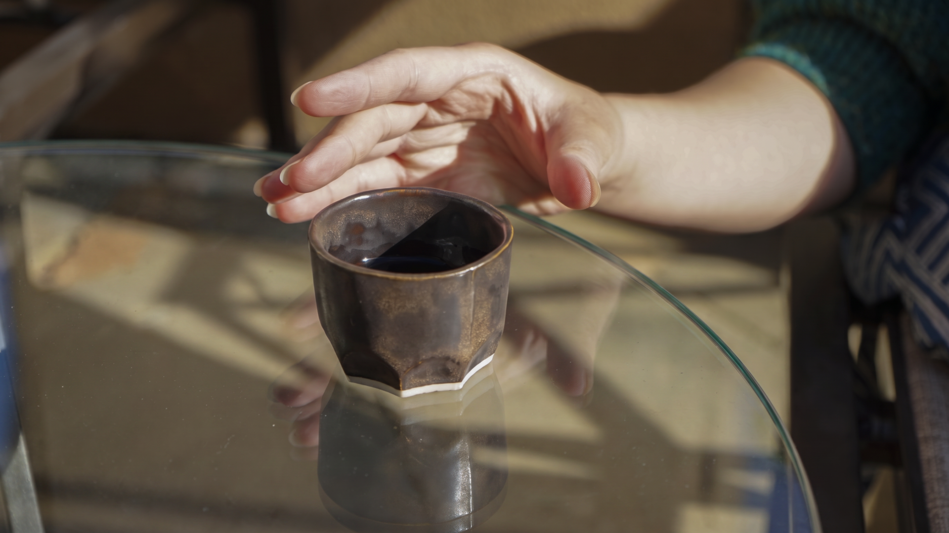 Dark bronze glazed tea cup on a glass table