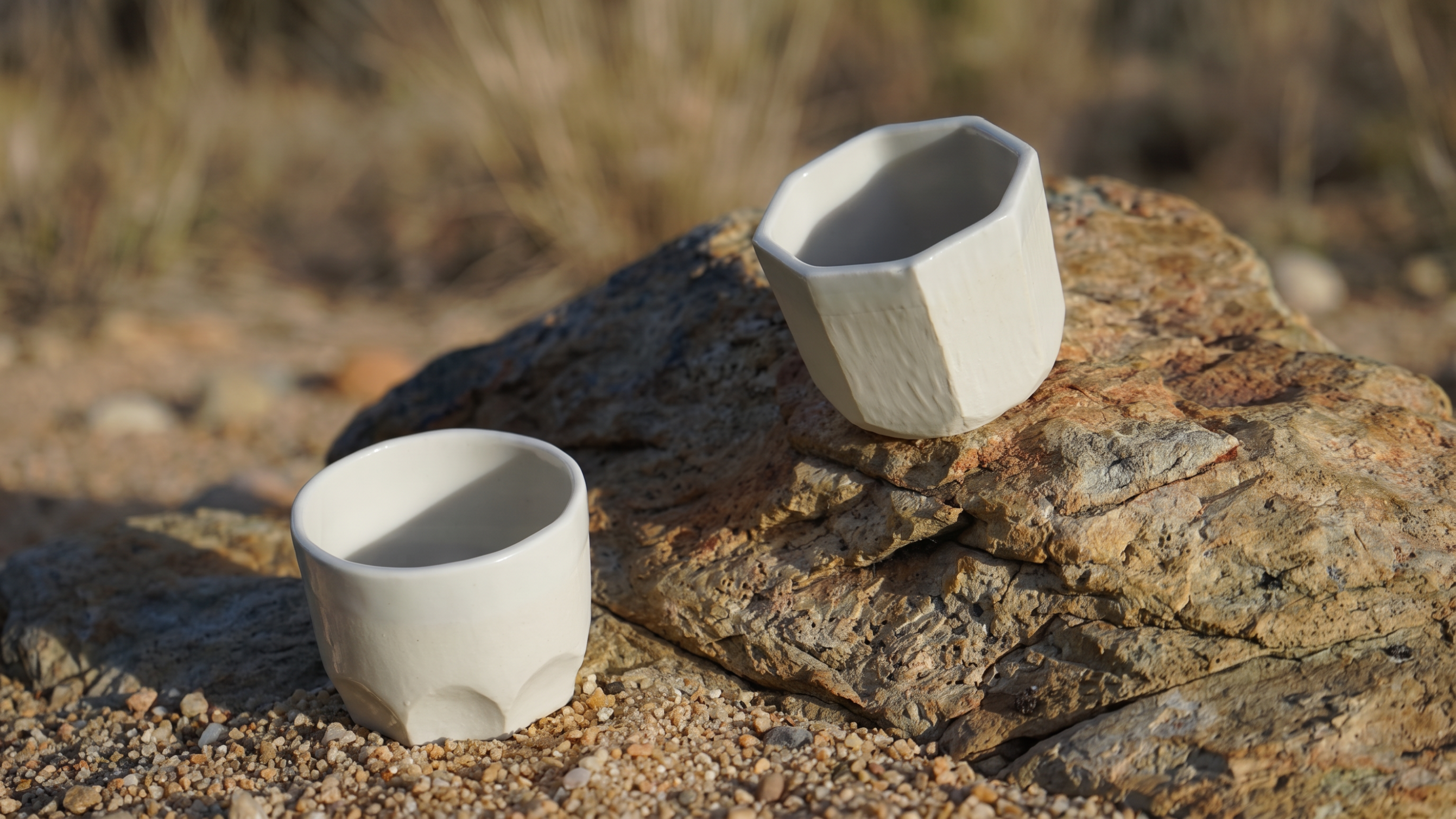 White faceted tea cups resting on a desert rock
